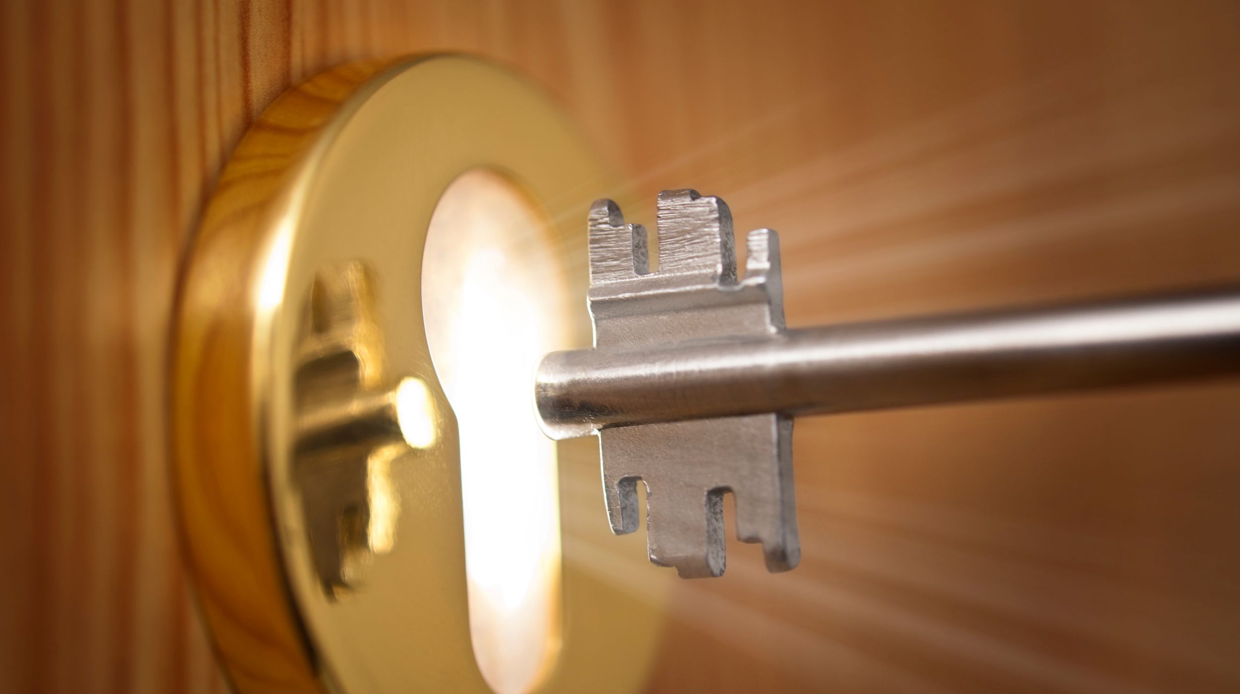 key being put in a lock with light coming out the keyhole