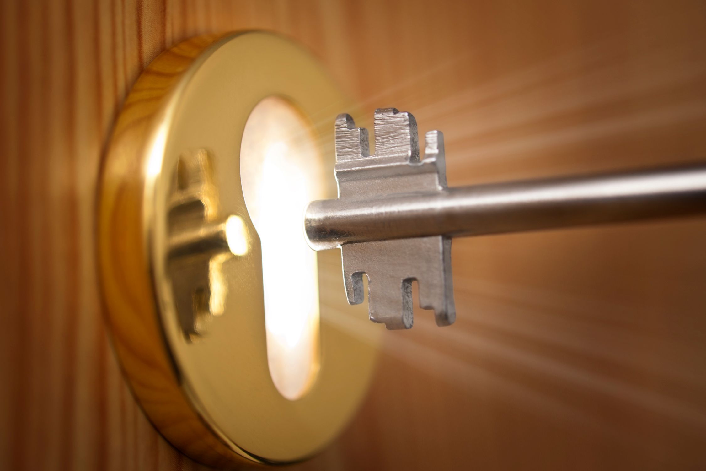 key being put in a lock with light coming out the keyhole