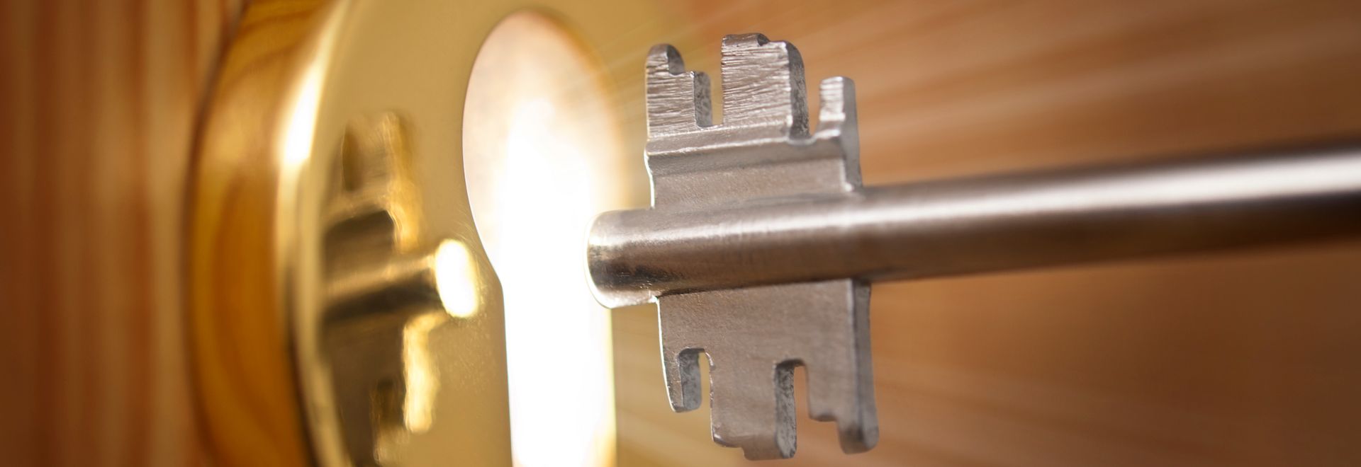 key being put in a lock with light coming out the keyhole